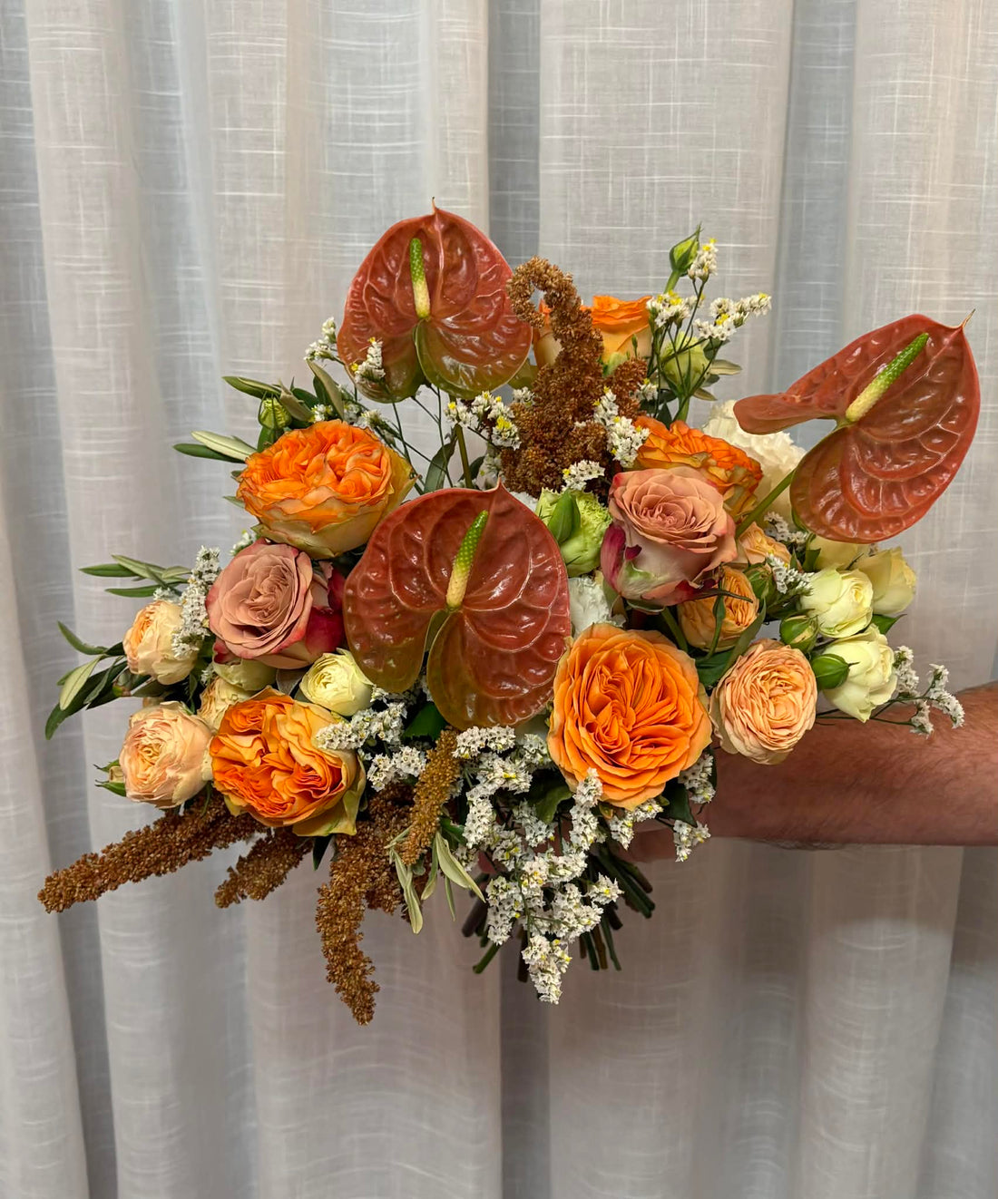 bold warm bridal bouquet with anthiurium and bright orange roses. 